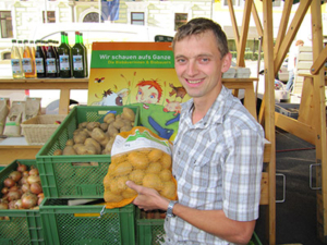 Bio-Bauer Andreas Schmiedberger mit Kartoffeln vor seinem Stand am Wochenmarkt Perg.