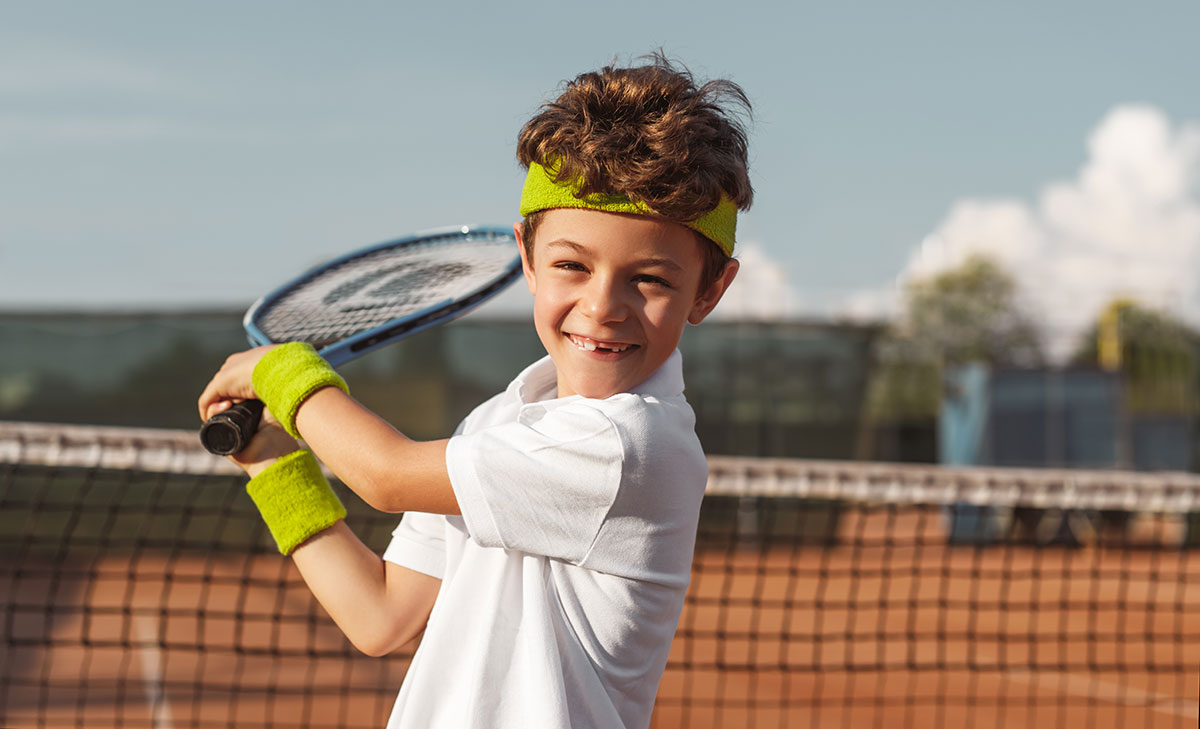 Tenniskurse in Perg: Ein glückliches Kind mit seinem Tennis-Racket