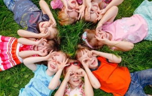 Ferienspaß in Perg - Gruppe von Kindern liegt auf der Wiese und blickt in den Himmel