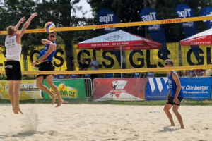 OÖ Beach-Finals 2025 in Perg bei besten Bedingungen - hier am Bild ein Mann der zum Ball hochspringt und zwei andere die ihn beobachten